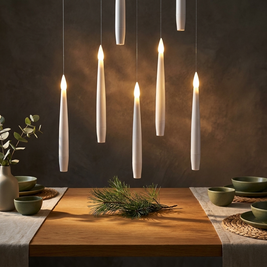 Set of flameless LED floating candles close-up, floating at different heights above an oak dining table