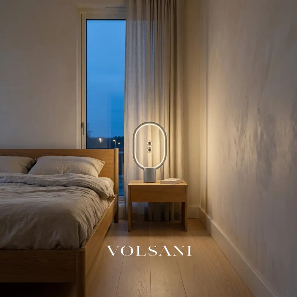Grey magnetic sphere lamp lit on a bedside table in a Japandi bedroom at dusk