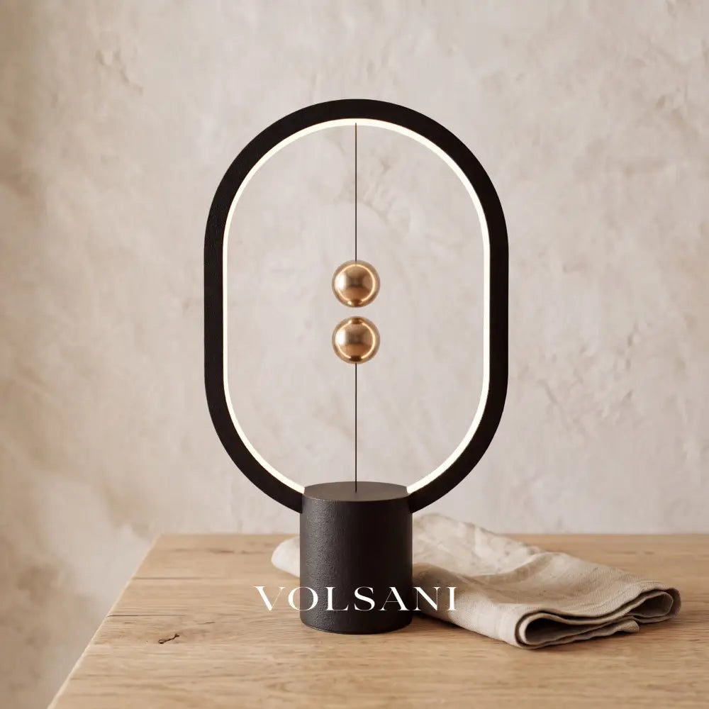 Close-up of the black magnetic sphere lamp on raw oak against a plaster wall