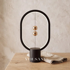 Close-up of the black magnetic sphere lamp on raw oak against a plaster wall