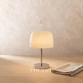 Close-up of the cream Bauhaus glass and chrome lamp on raw oak against a plaster wall