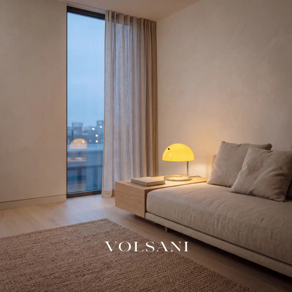 Yellow glass and chrome lamp lit beside a linen sofa in a Japandi living room at dusk