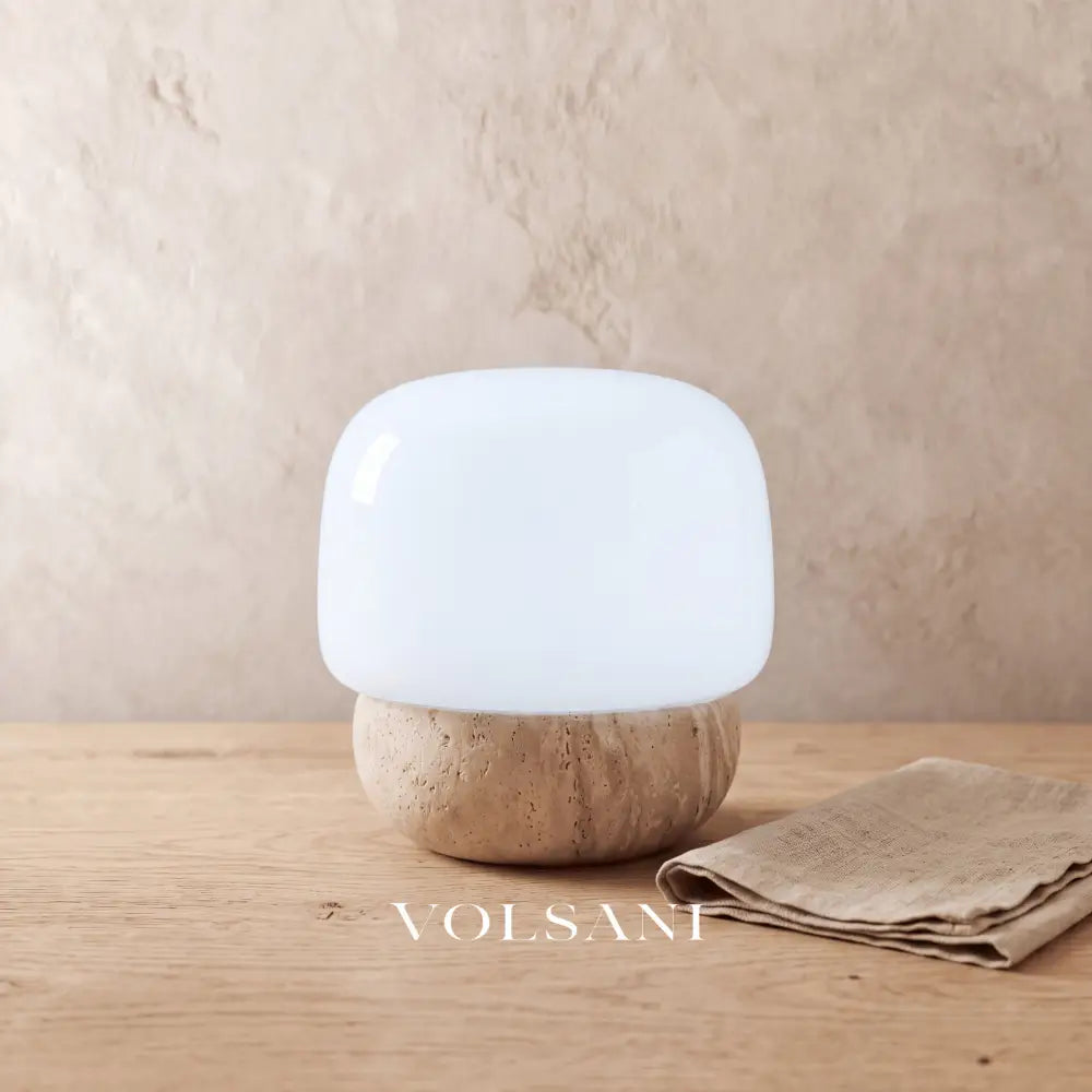 Close-up of the travertine mushroom lamp on raw oak against a plaster wall