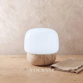 Close-up of the travertine mushroom lamp on raw oak against a plaster wall
