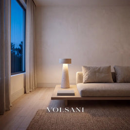 Sculptural travertine lamp lit beside a linen sofa in a Japandi living room at dusk