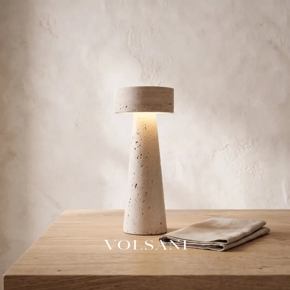 Close-up of the sculptural travertine lamp on raw oak against a plaster wall