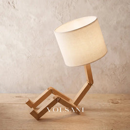Close-up of the wood lamp with poseable figure frame on raw oak against a plaster wall