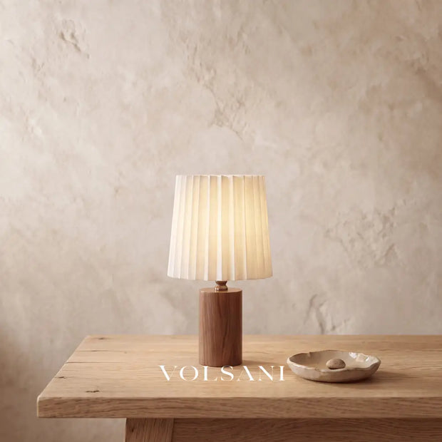 Close-up of the walnut table lamp on raw oak against a plaster wall