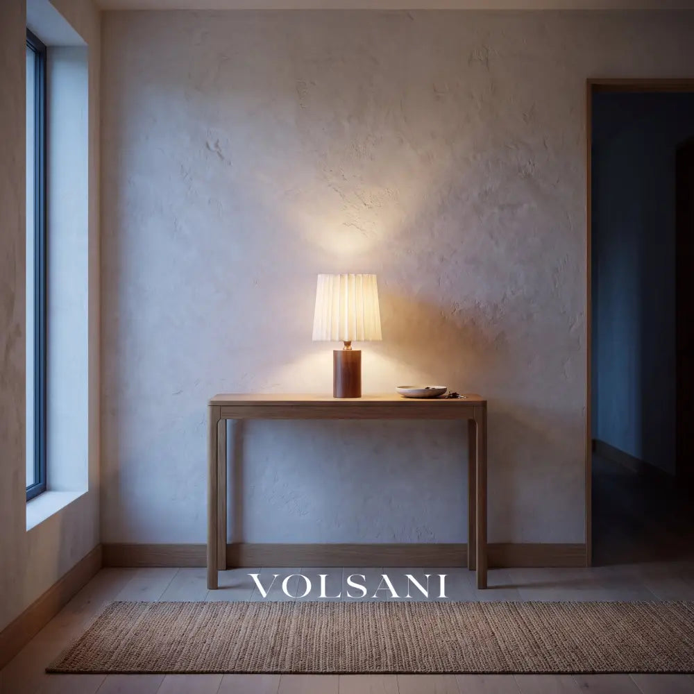 Walnut pleated-linen lamp lit on a console in a Japandi entrance hall at dusk